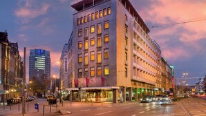Un hotel de varios pisos con fachada moderna, ventanas grandes y una entrada destacada.