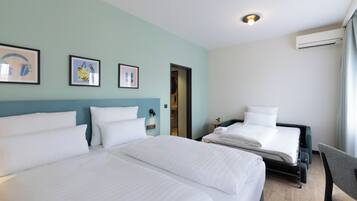 A hotel room with two beds, a desk, a chair, and a door leading to another room.