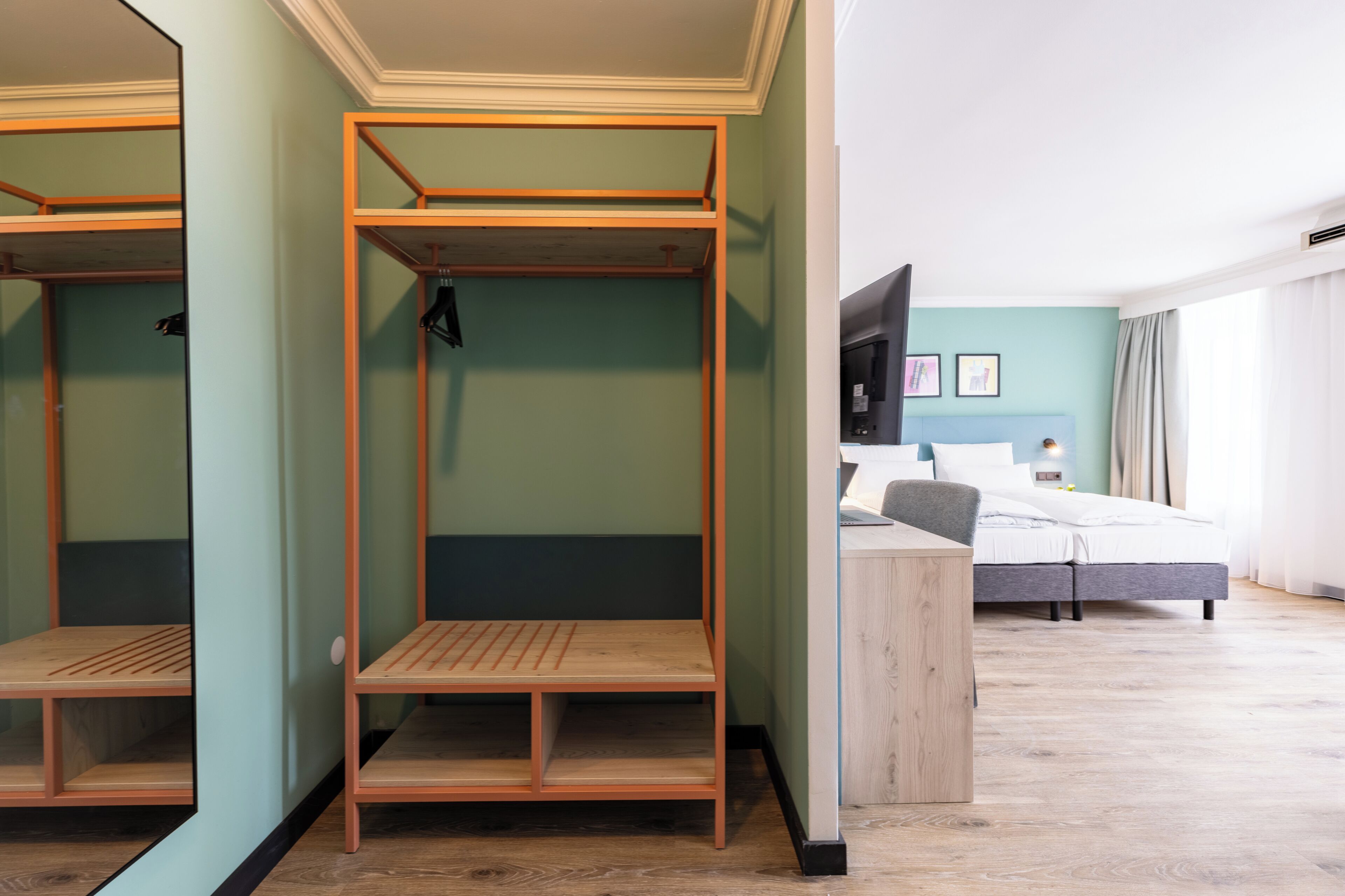 Habitació d'hotel amb llits superposats, escriptori, llit, televisió i finestra amb cortines.