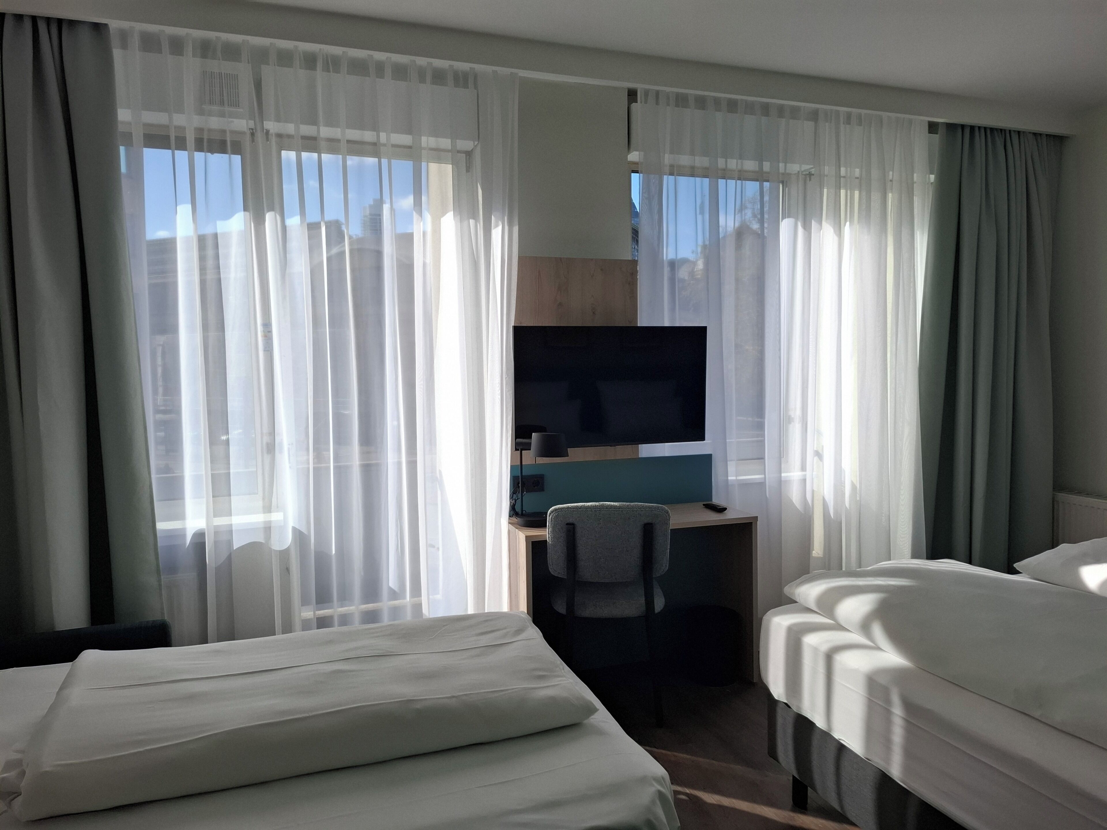 A hotel room with a bed, a desk with a computer, and a TV.