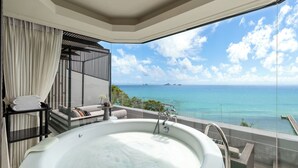 Une salle de bain moderne dotée d’une grande baignoire, d’une douche à parois de verre et offrant une vue sur l’océan.