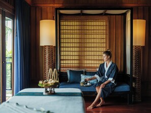 A room with a bed, a sofa, and a table with a tea set.
