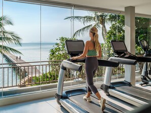 A woman walking on a treadmill with a view of the ocean and palm trees.