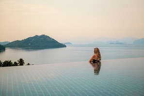 A person sitting on an infinity pool overlooking a calm body of water and distant islands. - InterContinental Koh Samui Resort by IHG (Koh Samui)