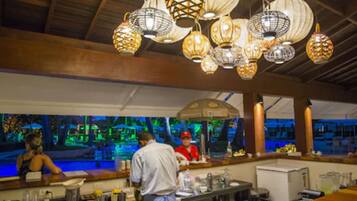 A restaurant with a bar area, wooden ceiling, and hanging lanterns.