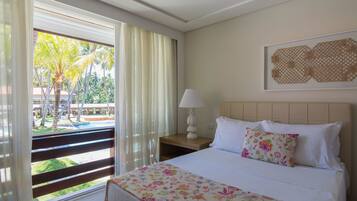 Una habitación de hotel con cama, mesita de noche, lámpara, ventana con cortinas y una obra de arte colgada en la pared.