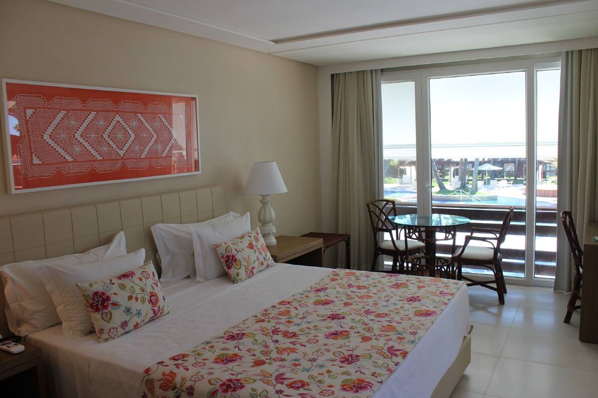 Habitación de hotel con una cama grande, una mesa de comedor y vistas a la ciudad.