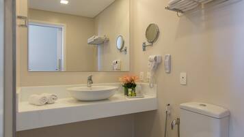 Un baño moderno con lavamanos, espejo y retrete blancos.