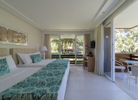 Habitación de hotel con una cama grande, un escritorio y un balcón con vista a palmeras.