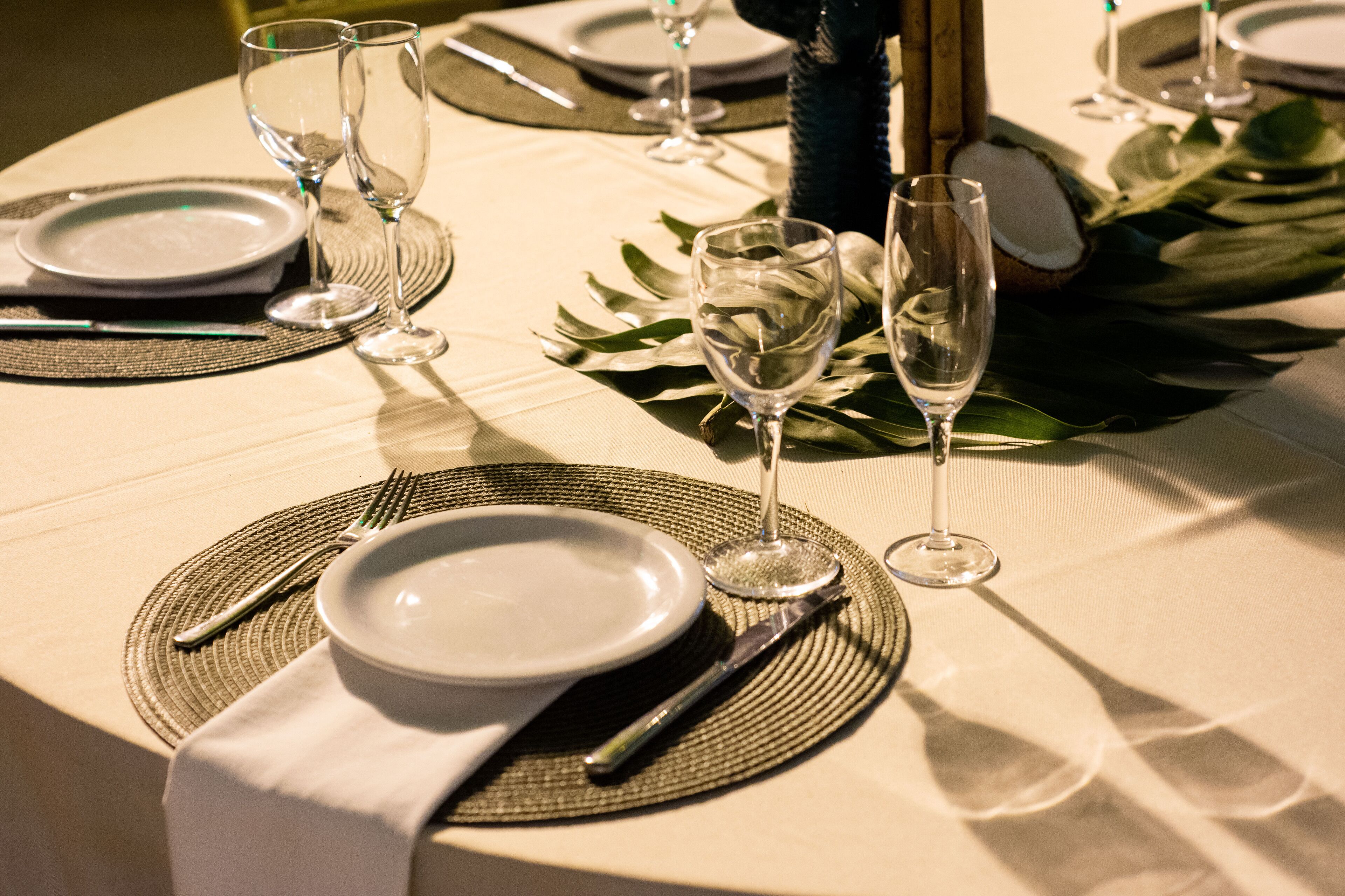 A table set for a formal dinner with white plates, cutlery, and wine glasses.