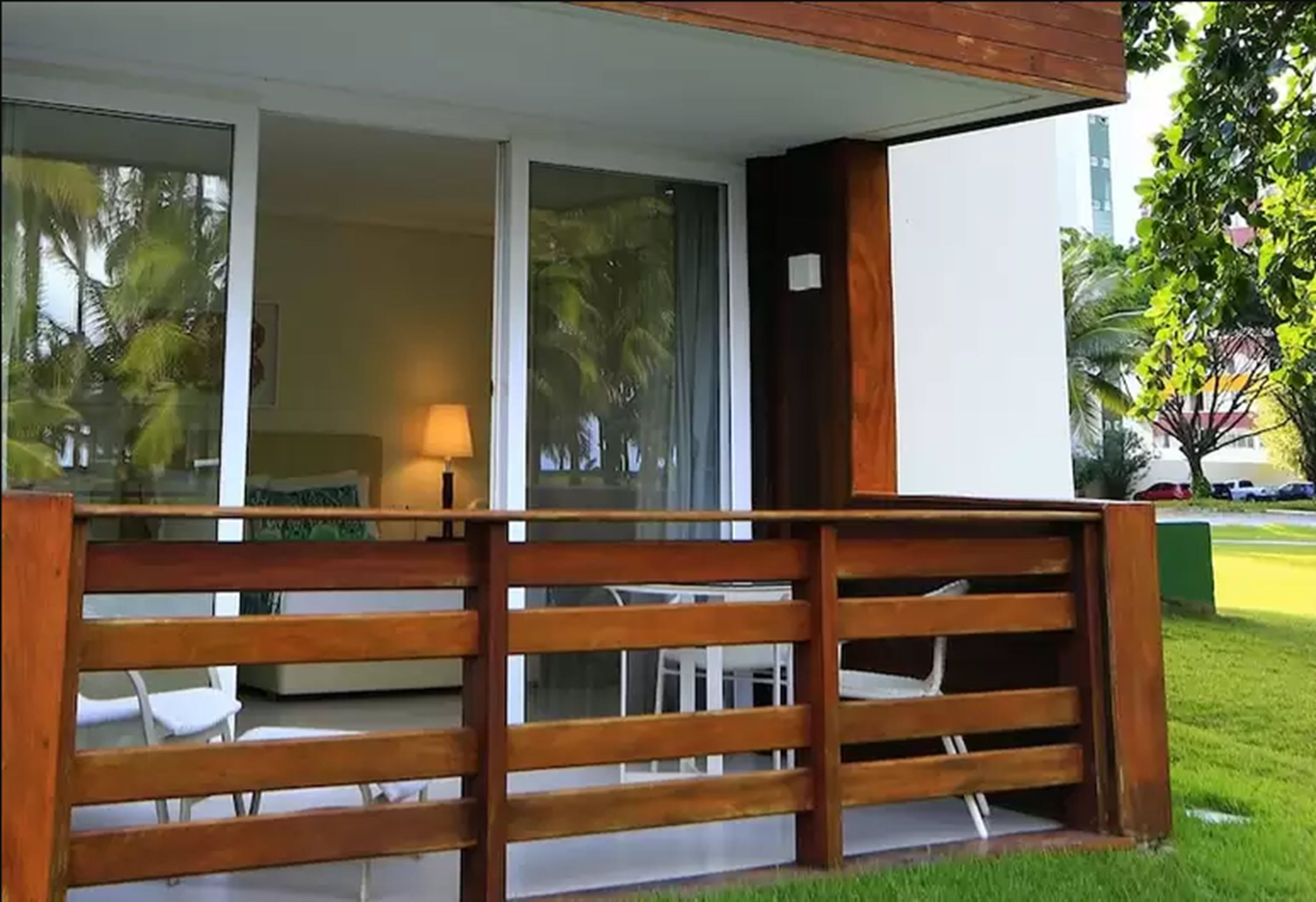 Un balcón de madera con vista a una habitación que tiene una cama y una lámpara.