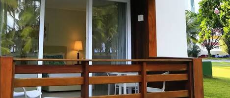 Un balcón de madera con vista a una habitación que tiene una cama y una lámpara.