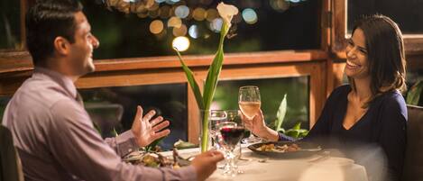 A couple dining at a table with a view of the city at night.