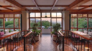 A dining area with wooden flooring, large windows, and potted plants. - Alta Las Palomas Hotel  (Santa Ana)