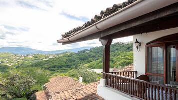 Un edificio con balcón que da a un paisaje verde exuberante y colinas distantes.