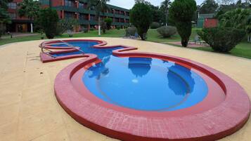 A swimming pool with a red and blue design, surrounded by a beige deck.