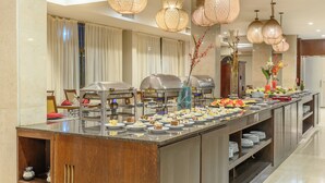 A buffet setup with multiple food stations, a central serving area, and hanging pendant lights. - Exe Hotel Cataratas (Puerto Iguazú)
