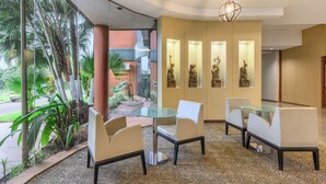 A modern hotel lobby with a glass partition, a round glass table, and white chairs. - Exe Hotel Cataratas (Puerto Iguazú)