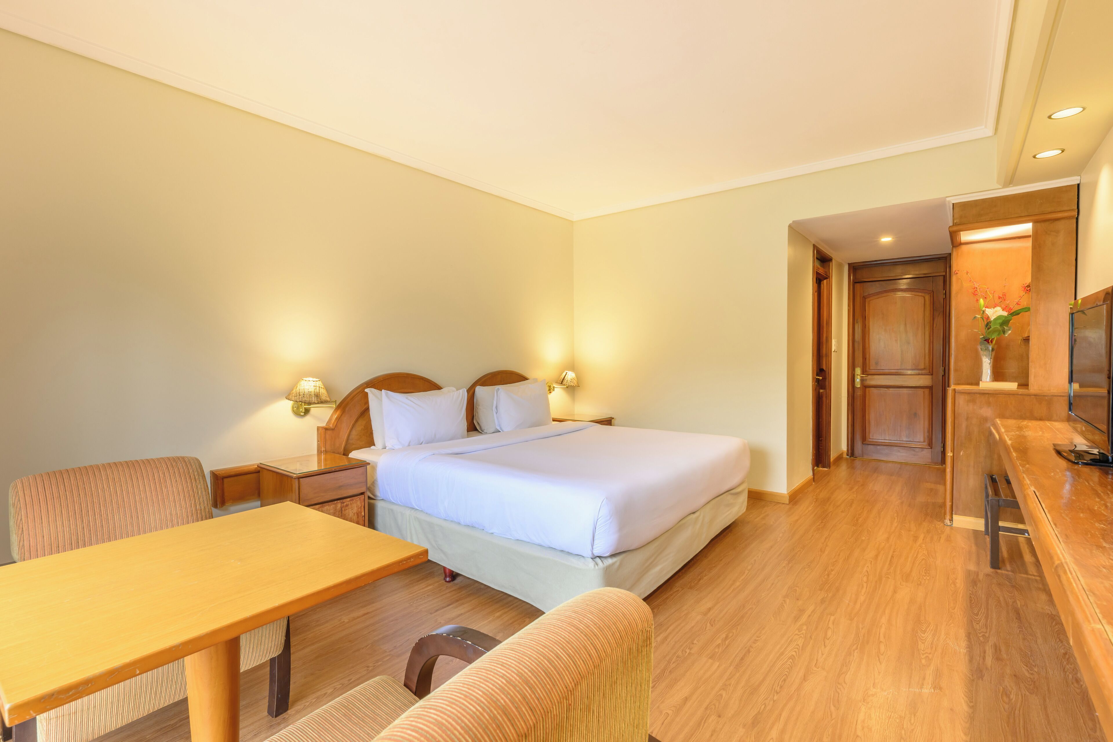 A hotel room with a bed, bedside tables, a desk, and a chair.
