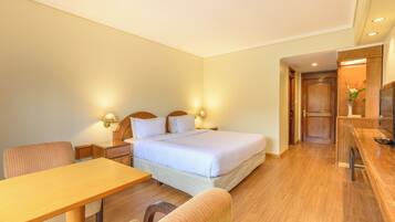 A hotel room with a bed, bedside tables, a desk, and a chair.