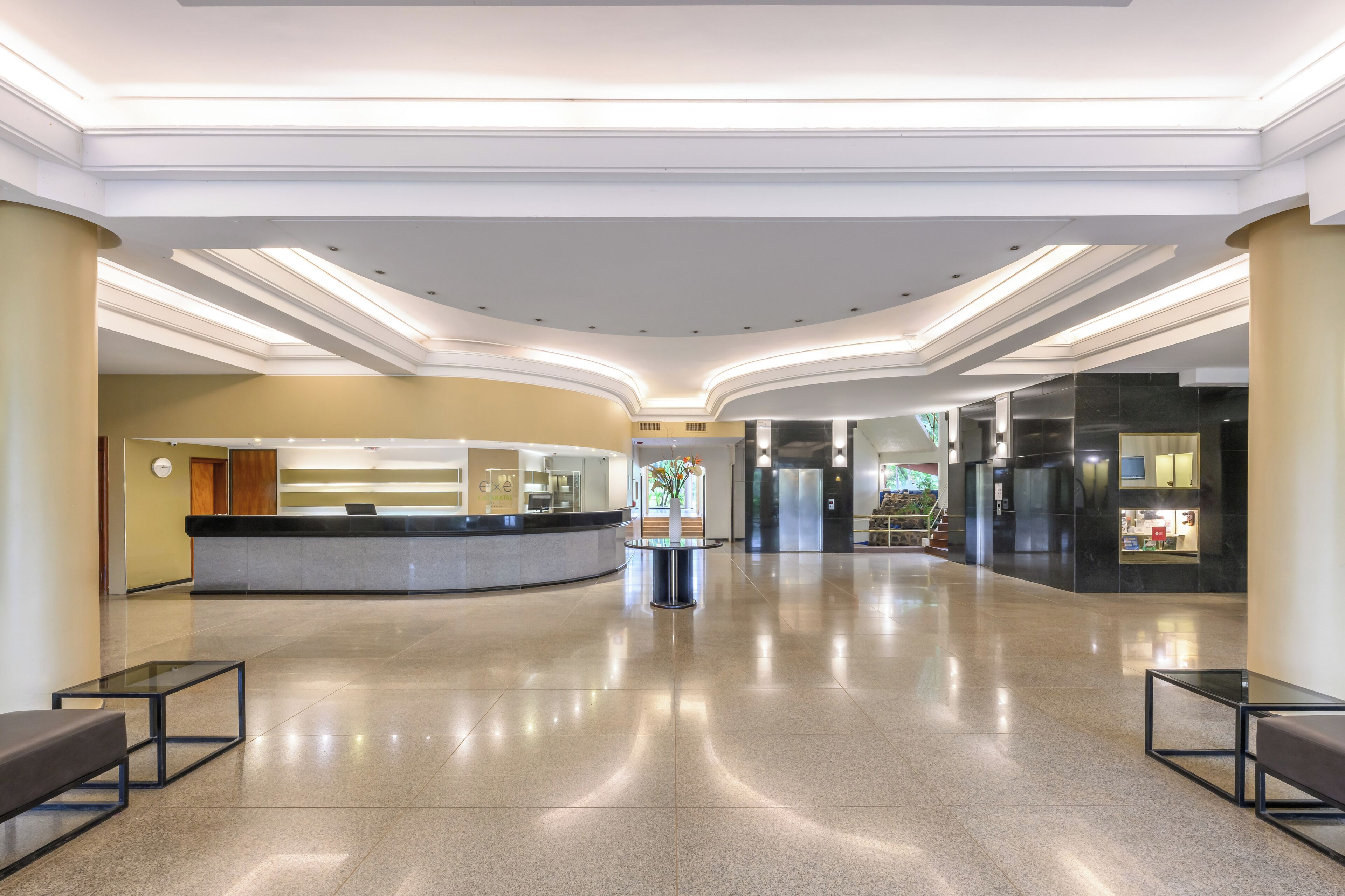 Un hall amplio con mostrador de recepción, zona de estar y una escalera que sube a los pisos superiores.
