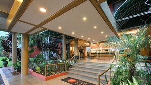 A hotel entrance with a covered staircase, indoor plants, and a reception area. - Exe Hotel Cataratas (Puerto Iguazú)