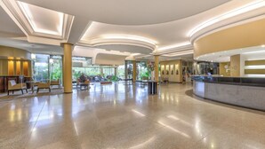 A spacious lobby with a reception desk, seating area, and large windows offering a view of the outdoors. - Exe Hotel Cataratas (Puerto Iguazú)