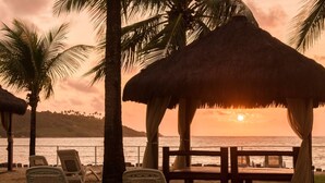 Une scène de plage avec une structure à toit de chaume, des palmiers et un banc.