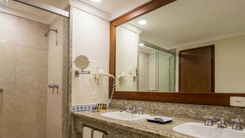 A bathroom with two sinks, a shower, and a large mirror.