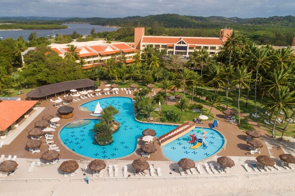 Relax by the resort's inviting pool surrounded by lush greenery and palm trees.