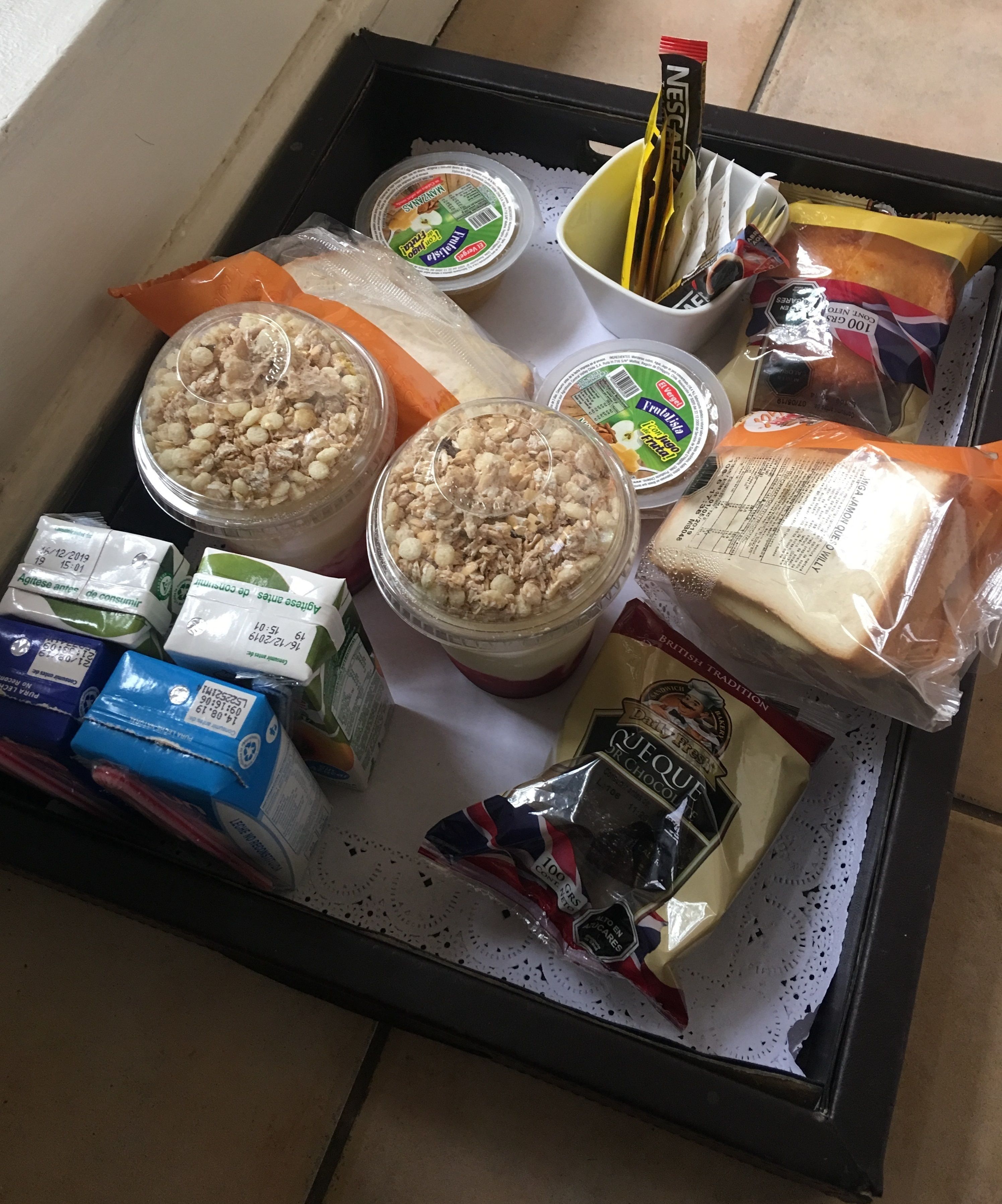 Un plateau contenant divers aliments, notamment des céréales, du yaourt et du pain.