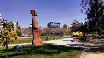 A sculpture in a park with a clear sky and buildings in the background.