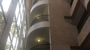 Un atrio de varios niveles con balcones, ventanas amplias y un elemento de iluminación central.