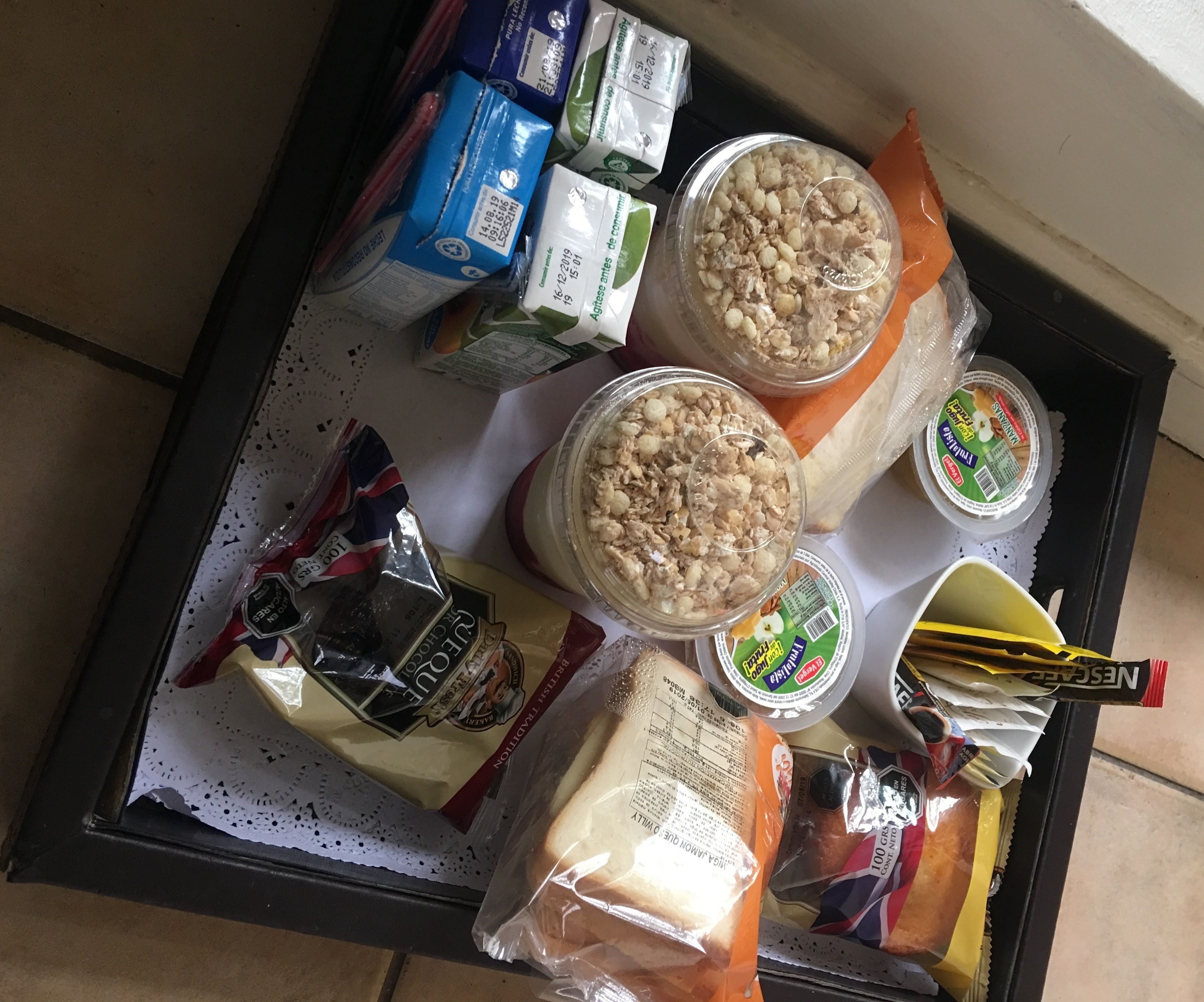 Uma bandeja com diversos alimentos, incluindo cereais, iogurte e pão.