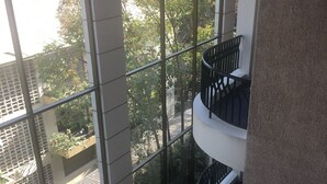 Un edificio de varios niveles con grandes ventanales que ofrecen vistas a árboles y una carretera.