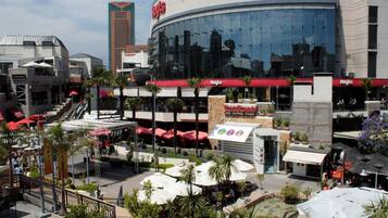 Un hotel con fachada de vidrio moderna, zonas de estar al aire libre con sombrillas y un letrero de restaurante visible.