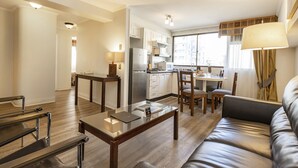 Una sala de estar moderna con un sofá de cuero, una mesa de centro de vidrio y un comedor con una mesa y sillas.