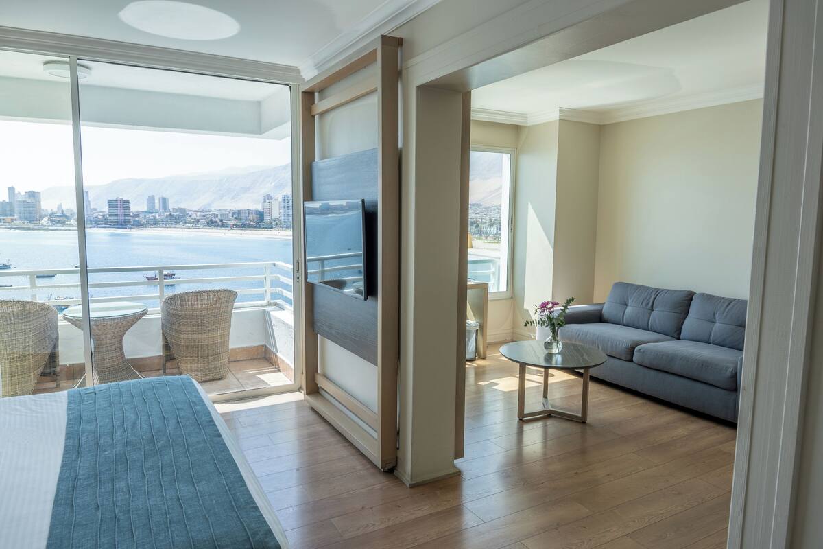 A modern living room with a balcony, a sofa, a TV, and a dining area.