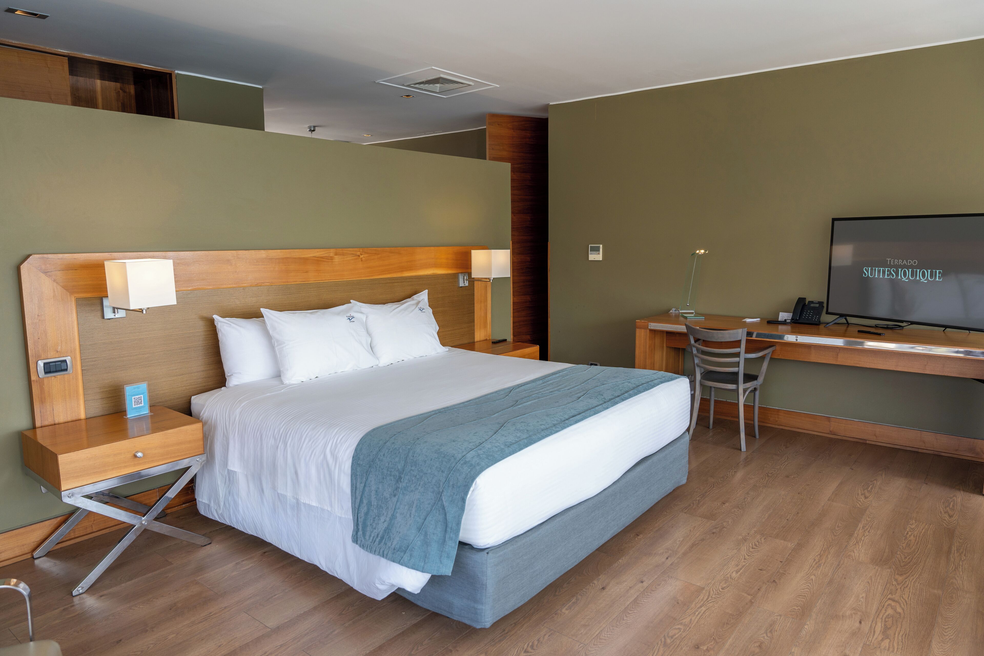 Ein Hotelzimmer mit einem Bett, einem Schreibtisch, einem Sessel, einem Fernseher und einem Nachttisch.