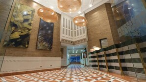 A hotel lobby with a checkered floor, hanging wicker chandeliers, and a large abstract painting on the wall. - Terrado Suites Iquique (Iquique)