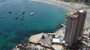 A coastal hotel with a pool, adjacent beach, and boats in the water. - Terrado Suites Iquique (Iquique)