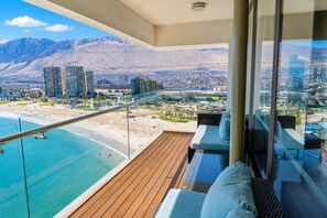 A balcony with a view of a beach and mountains, furnished with a sofa and chairs. - Terrado Suites Iquique (Iquique)