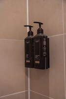 Dos botellas negras de jabón líquido y champú acondicionador Terranea sobre una pared de baldosas.