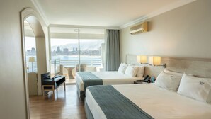 A hotel room with two beds, a desk, a chair, a view of the city, and a balcony. - Terrado Suites Iquique (Iquique)