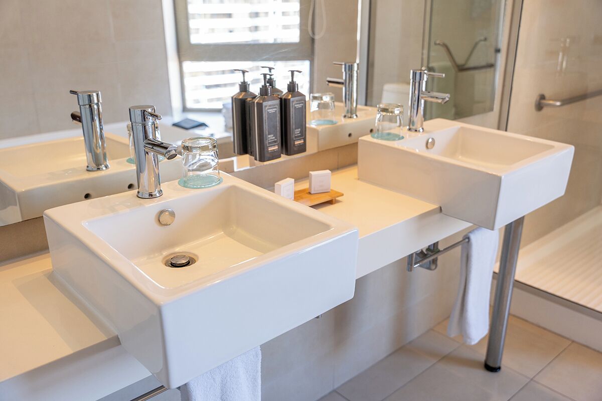 Een moderne badkamer met twee wasbakken, een douchecabine van glas en een grote spiegel.