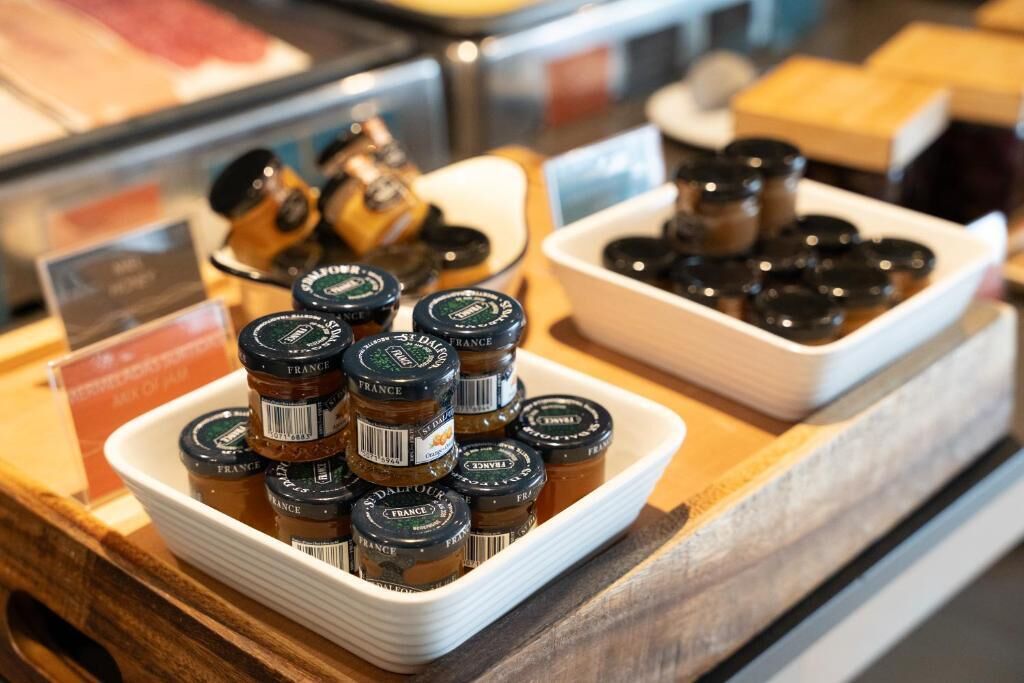 A display of small jars with labels, possibly containing condiments or preserves, arranged on a white tray.