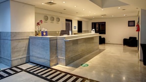 Un espace d’accueil d’hôtel avec un comptoir en marbre, des horloges et un extincteur.