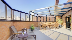 Une terrasse sur le toit, dotée d’une structure en verre, de sièges et de plantes en pot.