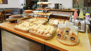 Un buffet proposant une variété de pains, de viennoiseries et un gâteau.