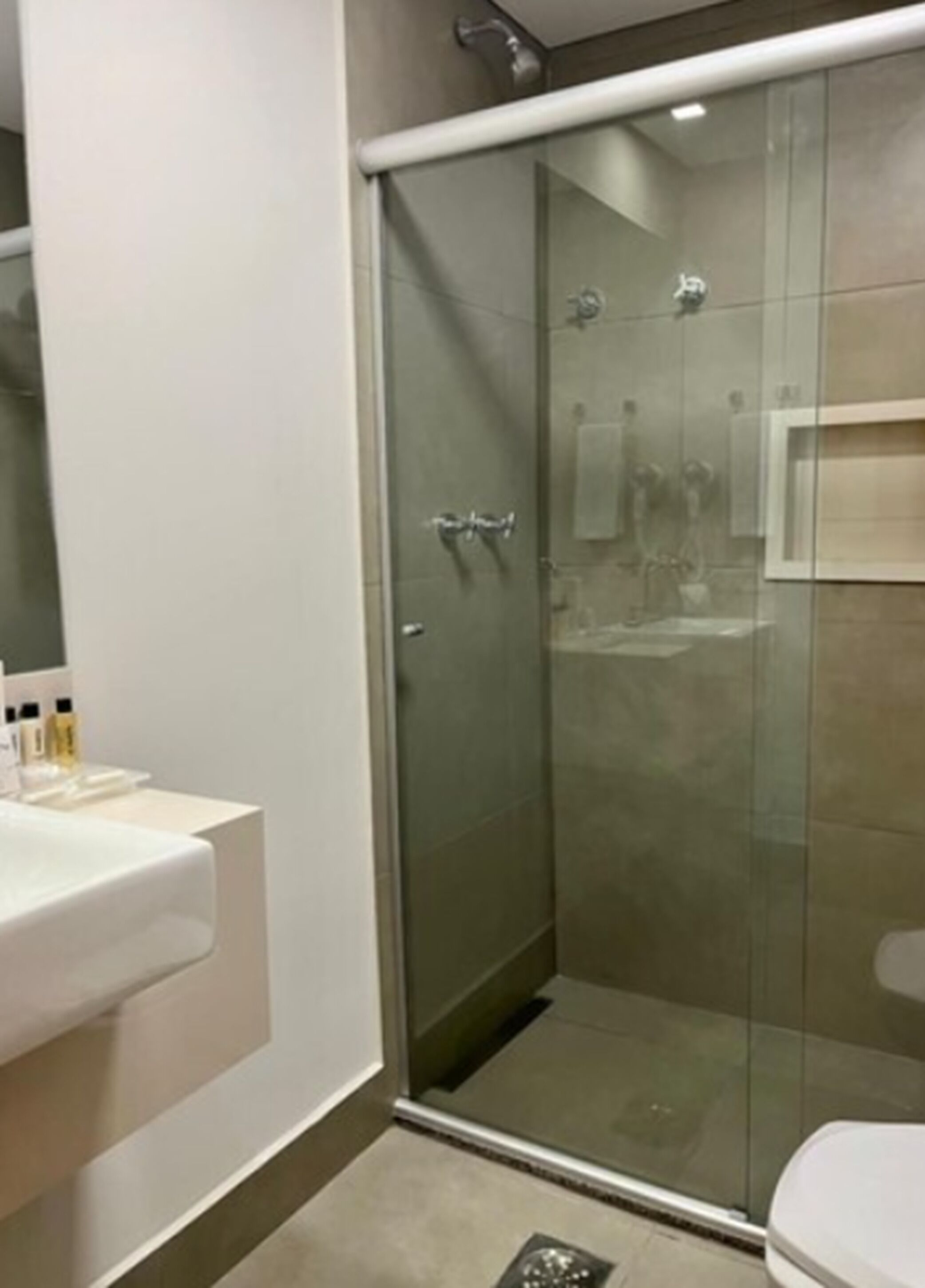 A modern bathroom with a glass-enclosed shower, a white sink, and a toilet.